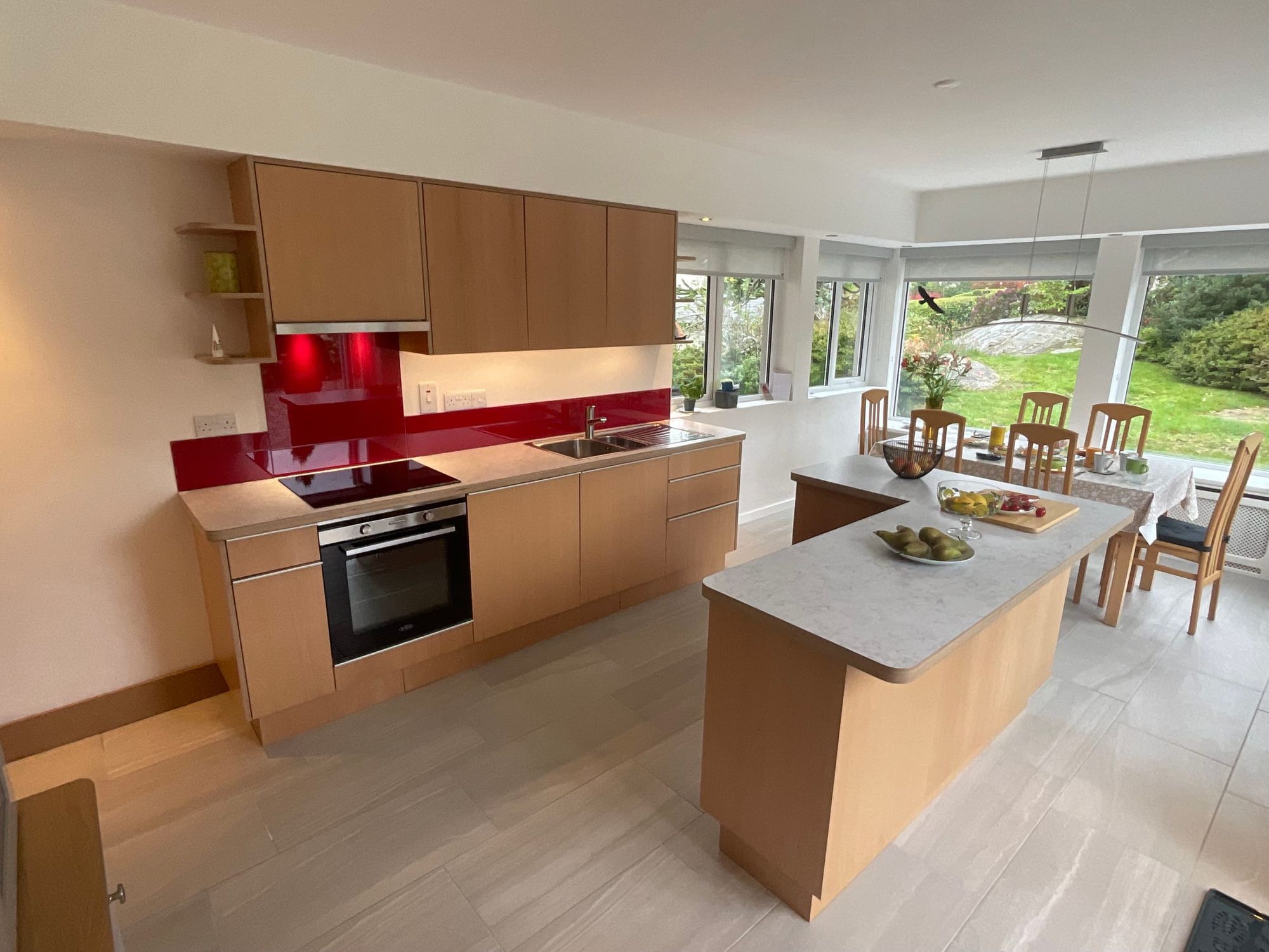 Kitchen with an island and a red glass splashback