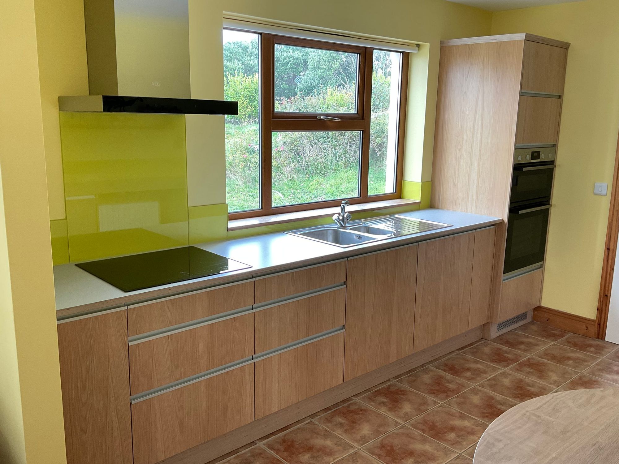 Kitchen with a green splashback and a tall oven housing