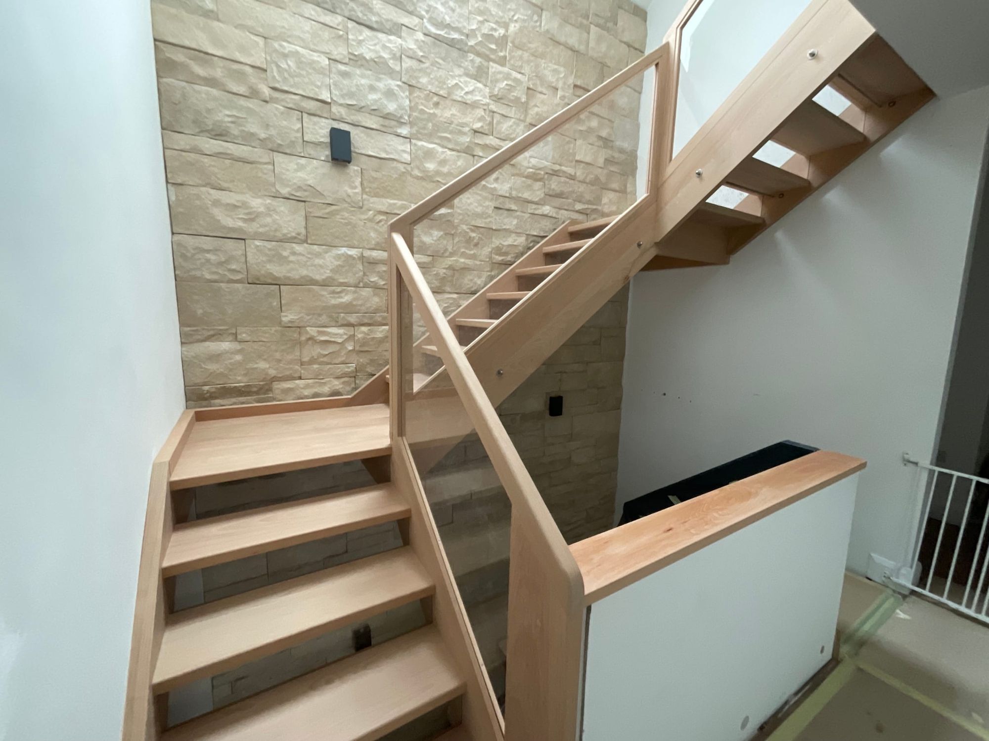 Stair with open treads turning at a landing, against a stone wall